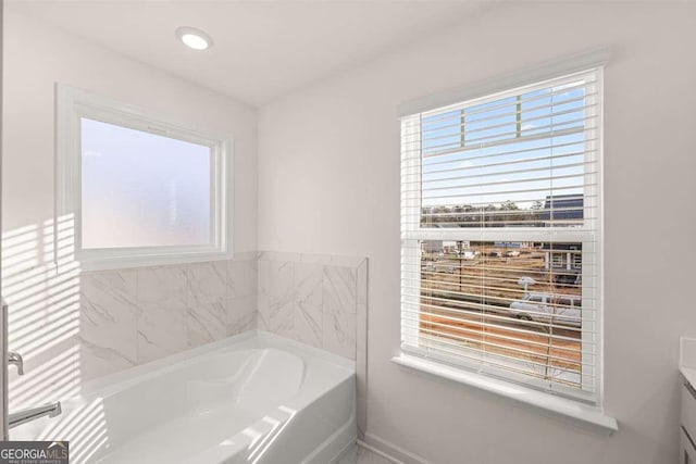 bathroom with a bathtub, a wealth of natural light, and vanity