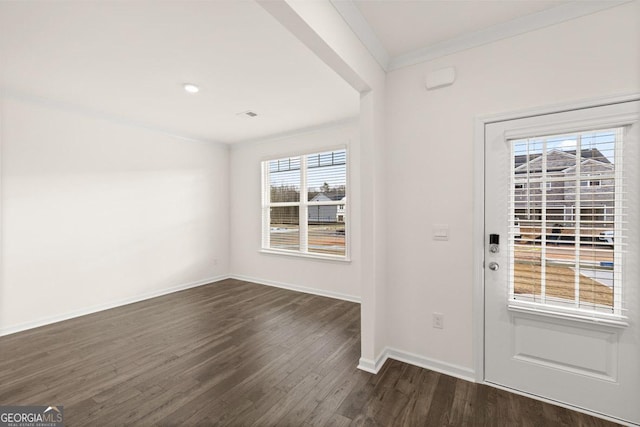 foyer with dark wood-type flooring, ornamental molding, and a healthy amount of sunlight