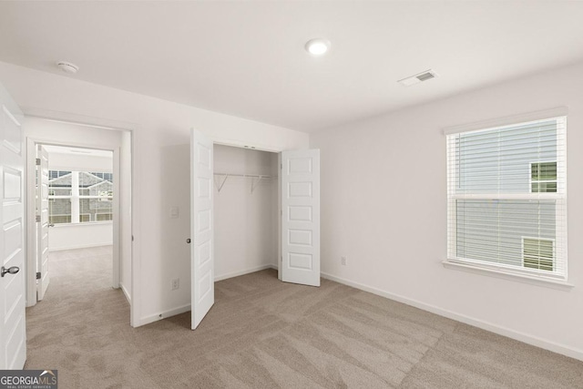 unfurnished bedroom featuring a closet and light carpet