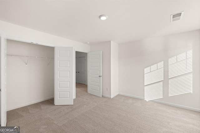 unfurnished bedroom featuring light colored carpet and a closet