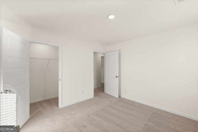 unfurnished bedroom featuring light colored carpet and a closet