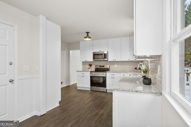 kitchen featuring sink, light stone countertops, a wealth of natural light, white cabinetry, and stainless steel appliances