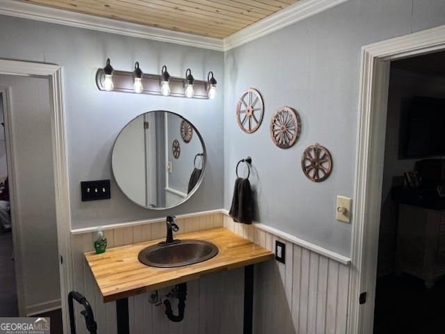 bathroom featuring crown molding, wooden ceiling, and sink