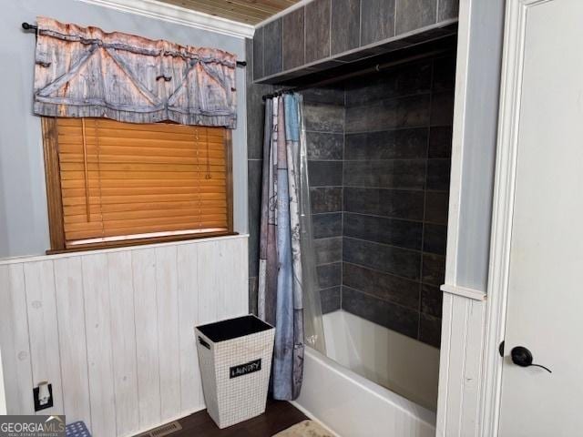 bathroom with wooden walls and shower / tub combo with curtain