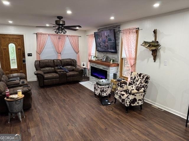 living room with dark hardwood / wood-style floors, a stone fireplace, and ceiling fan