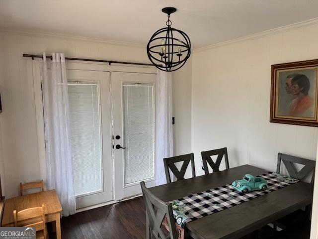 dining space with french doors, dark wood-type flooring, crown molding, and a chandelier