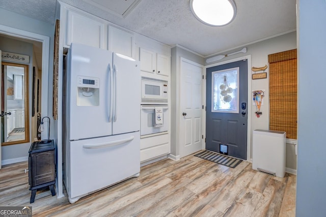 kitchen with white cabinets, light wood-type flooring, white appliances, and a textured ceiling