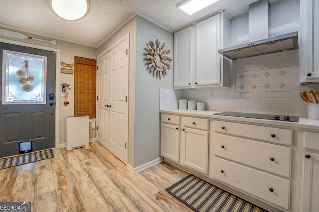 kitchen featuring black electric cooktop, white cabinetry, tasteful backsplash, and wall chimney exhaust hood