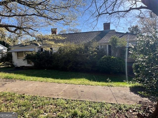 view of property exterior with a chimney and a yard