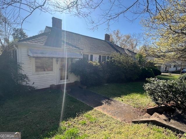 view of side of home with a lawn and a chimney