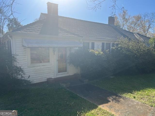 view of front of home with a chimney and a front yard