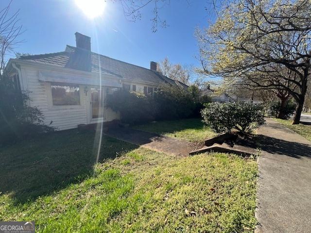 view of side of property with a chimney and a yard