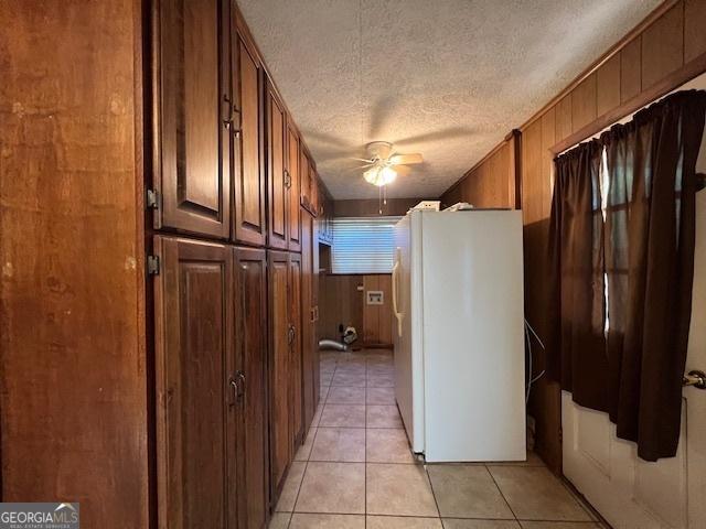 corridor featuring light tile patterned flooring, a textured ceiling, and wood walls