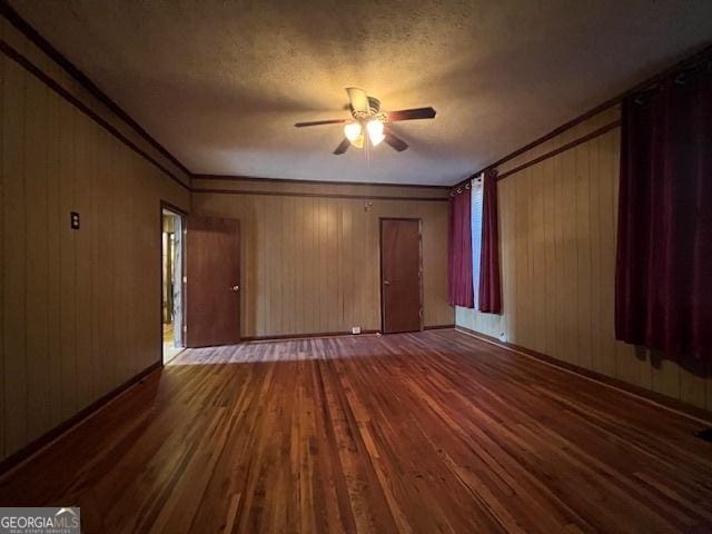 unfurnished living room with wood walls, wood finished floors, a textured ceiling, and ceiling fan