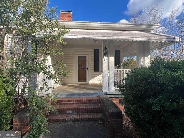 doorway to property with a chimney and covered porch