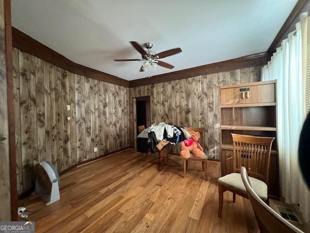 sitting room featuring ceiling fan, wood finished floors, and wooden walls