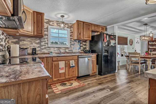 kitchen with dishwasher, black fridge with ice dispenser, hanging light fixtures, and sink