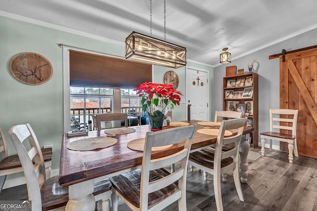 dining area with hardwood / wood-style flooring, a barn door, and ornamental molding