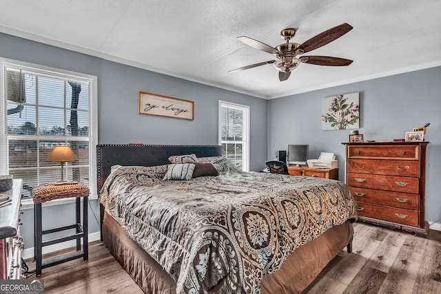 bedroom with ceiling fan, hardwood / wood-style floors, crown molding, and a textured ceiling