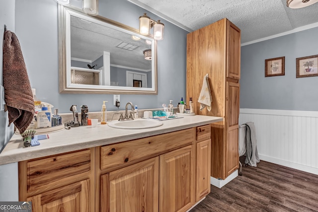 bathroom featuring vanity, ornamental molding, a textured ceiling, and hardwood / wood-style flooring