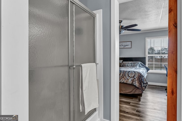 bathroom with hardwood / wood-style floors, ceiling fan, and a shower with shower door