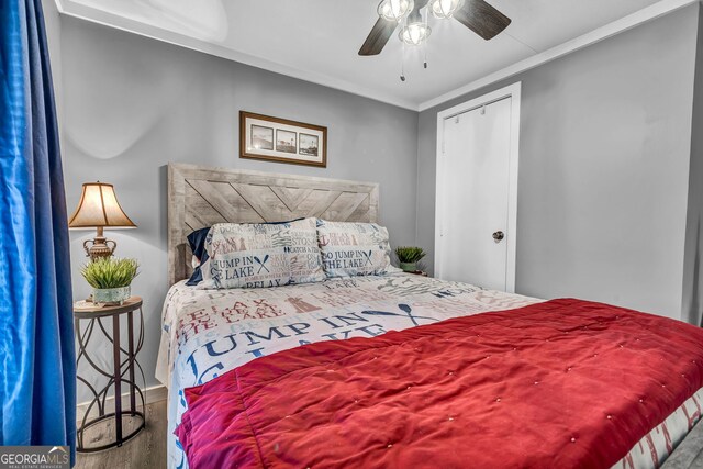 bedroom featuring hardwood / wood-style flooring, ceiling fan, crown molding, and a closet