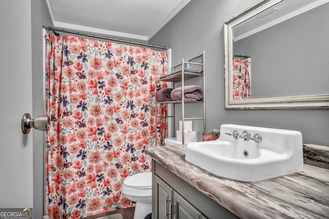 bathroom with curtained shower, vanity, a textured ceiling, and toilet