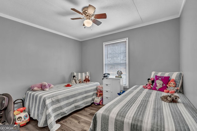 bedroom featuring wood-type flooring, a textured ceiling, ceiling fan, and crown molding