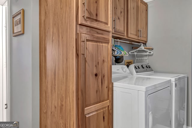 clothes washing area featuring cabinets and separate washer and dryer