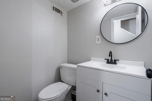 bathroom featuring toilet, vanity, and a textured ceiling