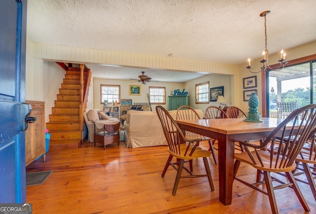 dining room featuring a textured ceiling, light hardwood / wood-style flooring, and ceiling fan with notable chandelier