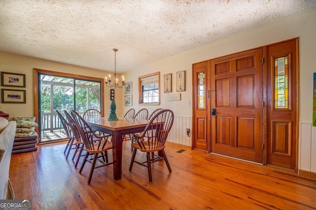 dining room with a textured ceiling, hardwood / wood-style flooring, and a notable chandelier