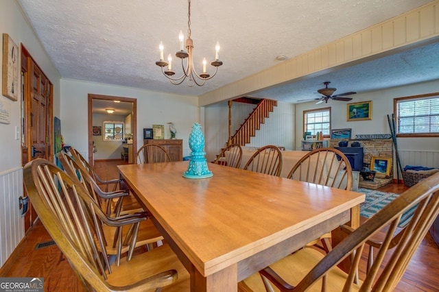 dining space with a textured ceiling, wood-type flooring, and ceiling fan with notable chandelier