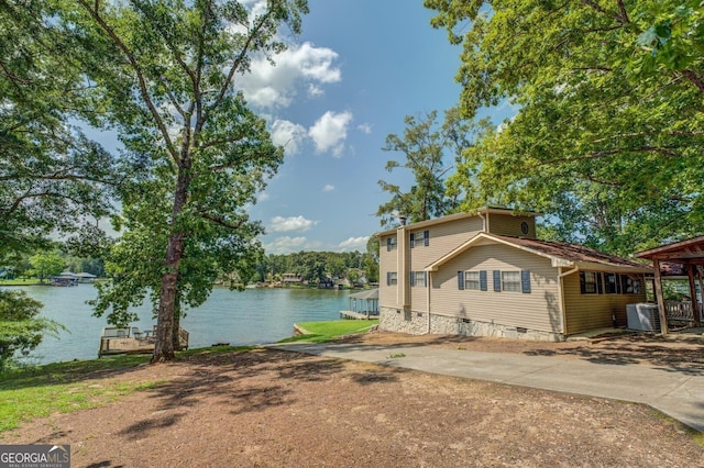 view of property exterior with central AC unit and a water view