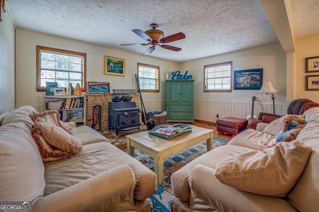 living room with a textured ceiling, a wood stove, and ceiling fan