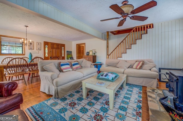 living room featuring ceiling fan with notable chandelier, wood-type flooring, and a textured ceiling