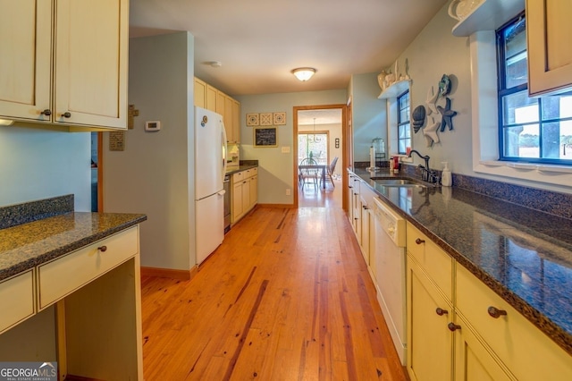 kitchen featuring white appliances, light wood-type flooring, sink, and dark stone counters