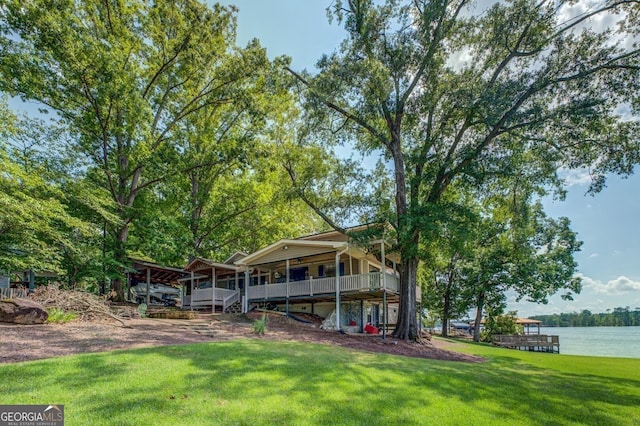 back of house with a lawn and a water view