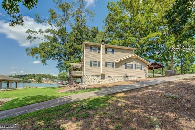 exterior space featuring a carport, a water view, and a yard