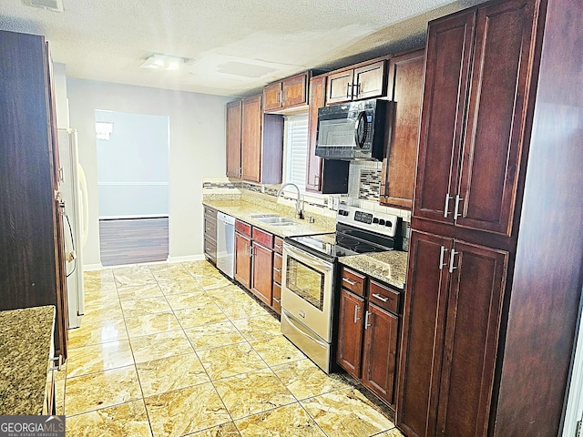 kitchen featuring a textured ceiling, light stone counters, sink, and appliances with stainless steel finishes