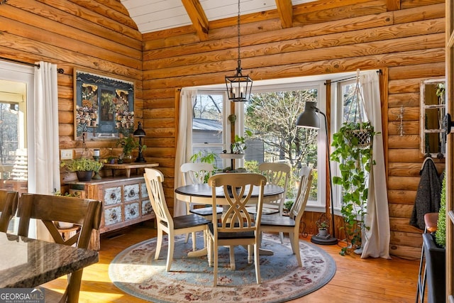 dining area with beamed ceiling, light wood-type flooring, high vaulted ceiling, and an inviting chandelier