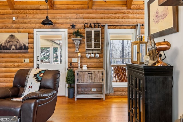 living area with light wood-type flooring, rustic walls, and a healthy amount of sunlight