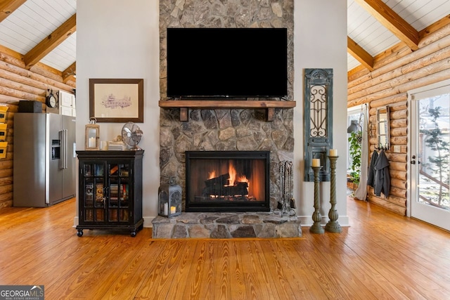 living room featuring hardwood / wood-style flooring, a healthy amount of sunlight, a stone fireplace, and log walls