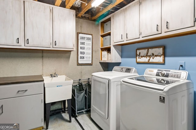 clothes washing area with separate washer and dryer and cabinets