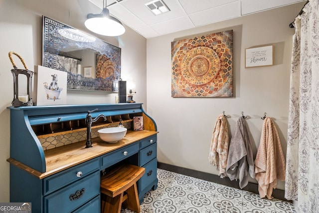 bathroom with tile patterned floors, vanity, and a drop ceiling