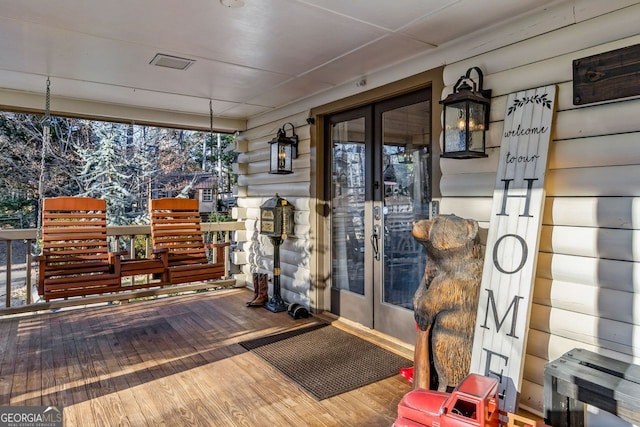 wooden terrace featuring french doors and a porch