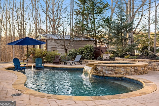 view of swimming pool with a patio area, pool water feature, and an in ground hot tub