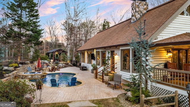 pool at dusk featuring an in ground hot tub, a gazebo, and a patio