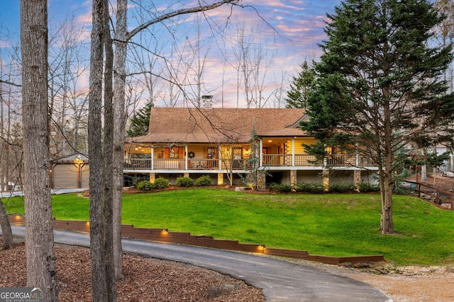 view of front of property featuring a porch, a garage, an outdoor structure, and a lawn