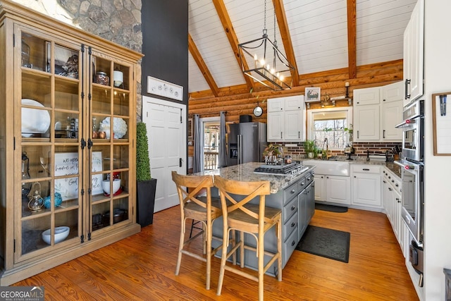 kitchen with a center island, high vaulted ceiling, white cabinets, sink, and stainless steel fridge